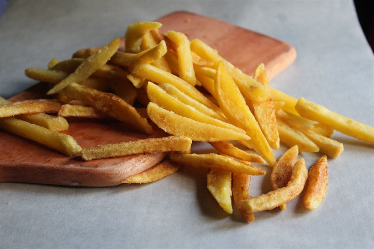 Batata frita sequinha sobre tábua de madeira