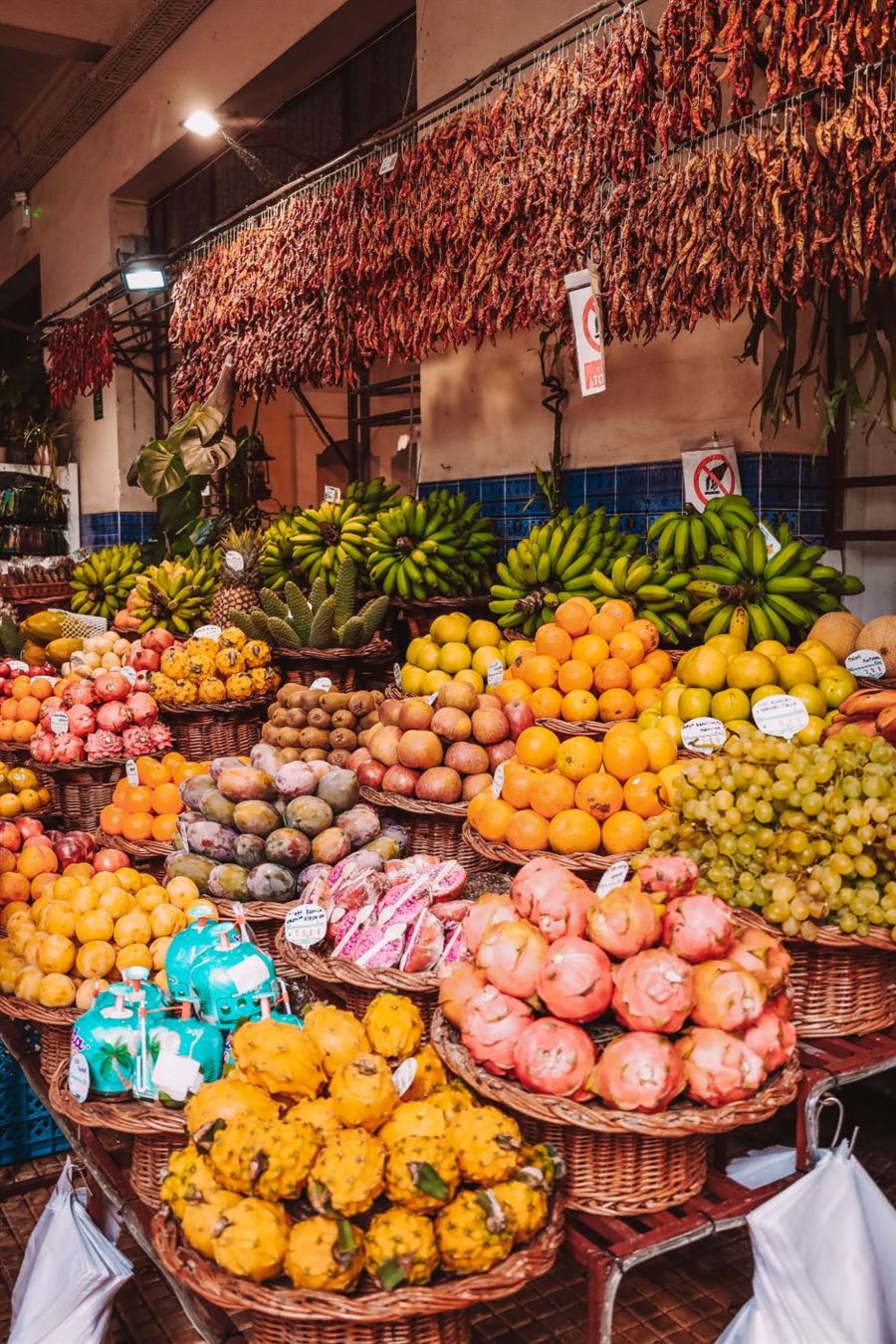 Banca de feira com bananas, laranjas, maracujás, pitaias e pimentas penduradas